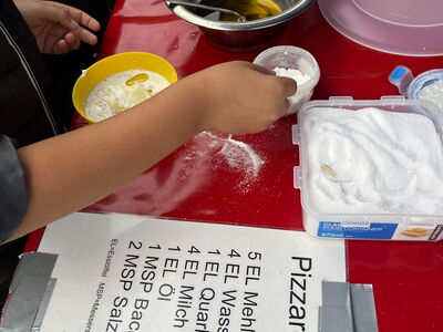 Kinder stellen einen Pizzateig her